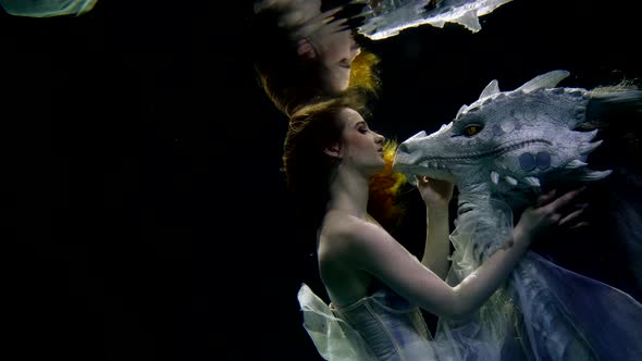 a Beautiful Girl with Long Loose Hair and in a Dress Swims Underwater with a Dragon As in a Dream