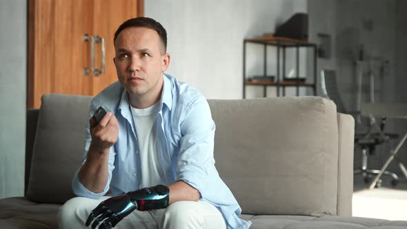 Cyborg guy with bio limb prothesis switches television channels with remote controller