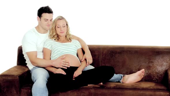 Young Expecting Parents on Couch With White Background