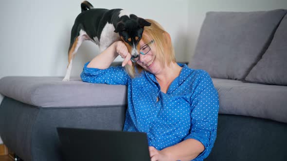A Woman Working on a Laptop While Sitting on the Floor with Her Cute Dog