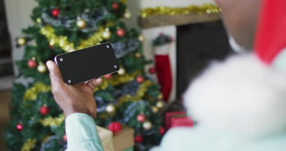 Happy mixed race senior woman on video call on smartphone with copy space at christmas time