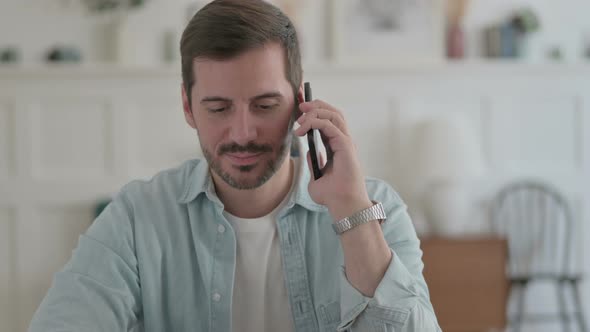 Young Man Talking on Phone Discussing Work