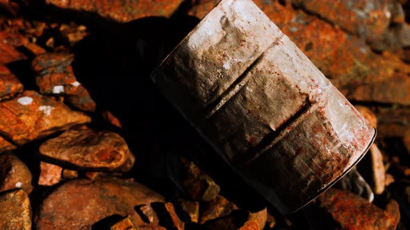 Rusty Destroyed Metal Barrel on Beach Rocks