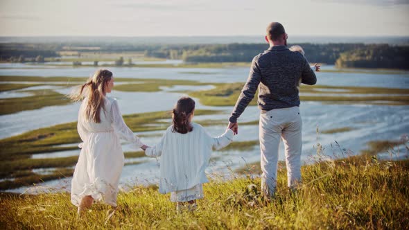 Young Family Standing on the Wheat Field and Holding Hands