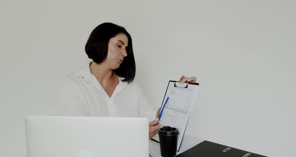 Lecturer Chatting on Laptop Using Notebook, Drinking Cup of Coffee in an Office