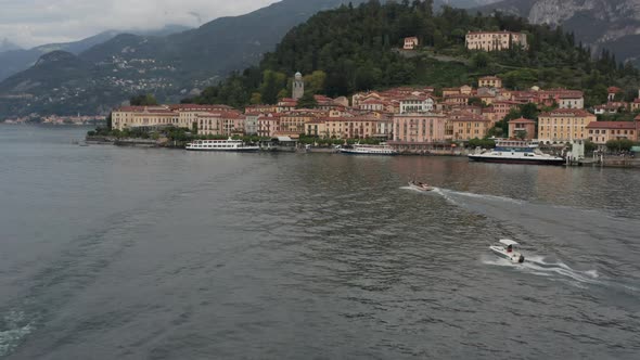 Flying towards boats on a busy lake near a beautiful Italian coastal city