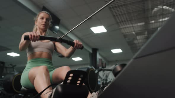 Low angle of caucasian woman exercising on rowing machine. Shot with RED helium camera in 8K.