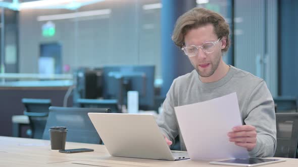 Businessman with Laptop Having Loss While Reading Documents