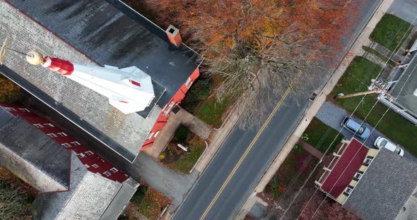 Top down aerial of church steeple in American village. Traffic drives by in small town neighborhood.