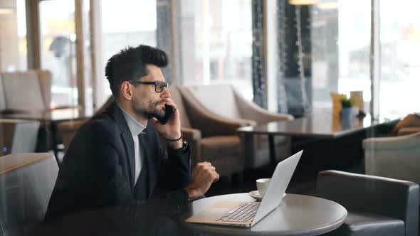 Serious Business Man Making Telephone Call Using Smartphone in Cafe