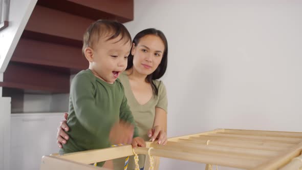 Asian Mom Watching Toddler Play on Climbing Frame at Home