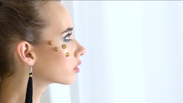 Model with Rhinestones on Her Face Posing in Front of the Cameras. Slow Motion