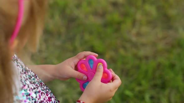 Closeup of Girl Playing Spinning with Pop It Sensory Antistress Toy in Park Stress Anxiety Relief