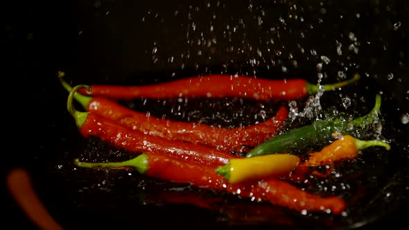 Chili peppers falling on wet surface, Ultra Slow Motion