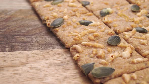 Crispbreads with pumpkin seeds and melted cheese closeup on a wooden rustic textured surface