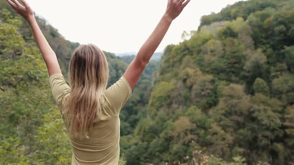 Girl with Raised Hands Looks at the Mountains. The Girl Stands Back and Looks at the View. Rest in