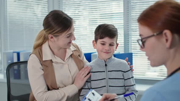 Health Care Happy Mom with Her Son at the Doctor Appointment Therapist Consults Patients and Talks