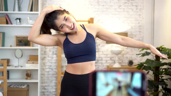 Asian Woman in Sportswear Talking to Camera and Explaining Fitness Tutorials Online in Living Room