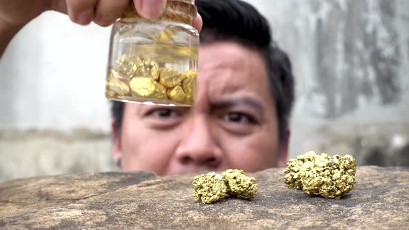 Asian man looking pure gold minerals found in mines in the bottle