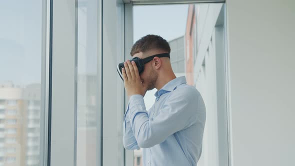 Close Up Young Man Sitting at a Desk in the Office Uses Augmented Reality Glasses To Work on