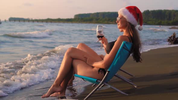 Happy girls in bikinis and baths celebrating Christmas on beach