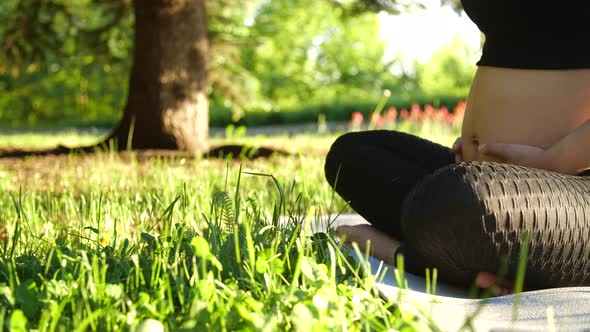 Maternity and Pregnancy Concept. Young Pregnant Woman Sitting on the Grass Doing Fitness or Yoga