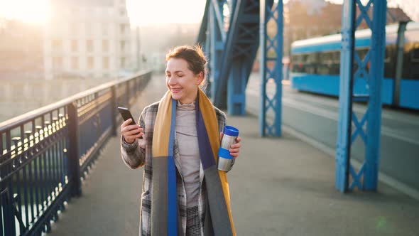 Portrait of a Young Caucasian Businesswoman in a Coat Walking Across the Bridge on a Frosty Morning