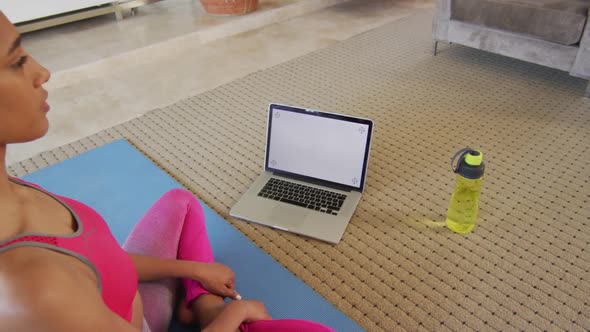 Mixed race woman practising yoga at home