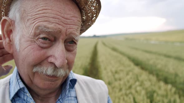 Macro Portrait of Wrinkled Senior Man Looking Thoughtfully and Taking Off Hat