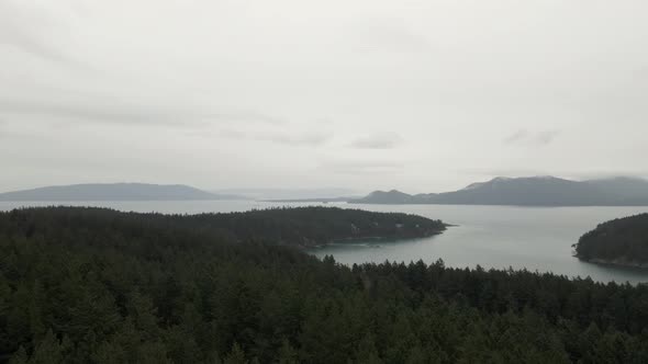 Typical gray clouds hang eerily over forest islands of the San Juans, Washington, aerial panorama
