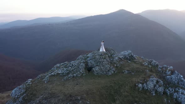 Aerial Drone Wedding Shot of a Bride in White Dress Standing on a  Mountain Peak