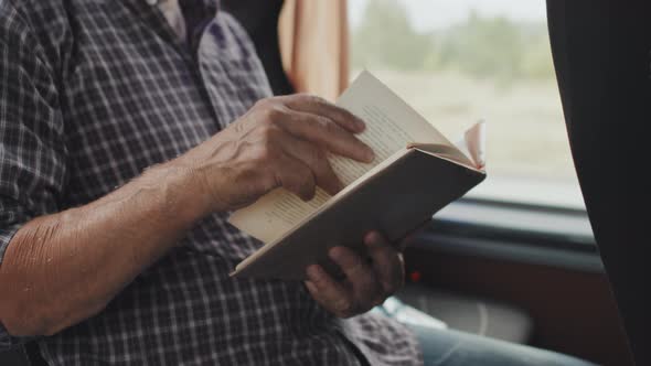 Midsection of Man Reading Book during Bus Ride