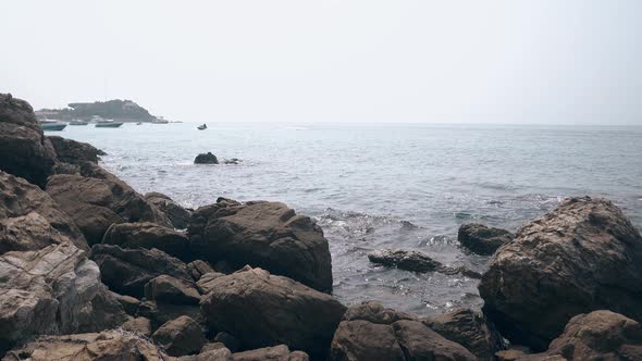 Ocean Splashes on Big Grey Stones and Distant Water Scooter