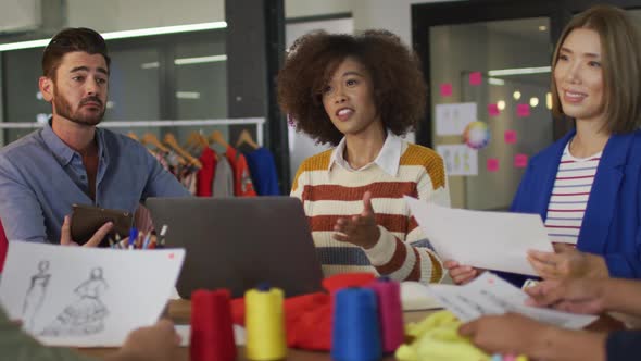 Mixed race colleagues sitting in office and discussing work over laptop