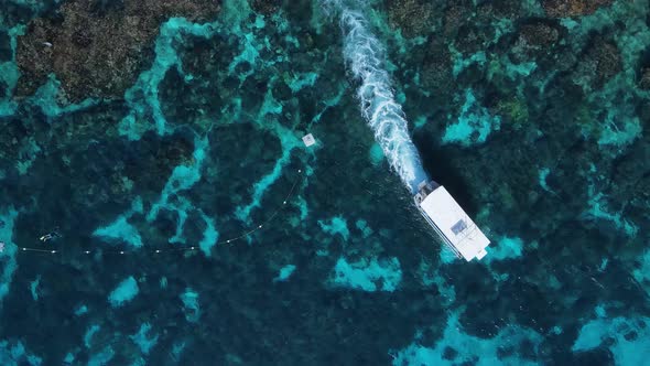 Unique view of a dive boat as ites through the water over a tropical reef system. High drone view