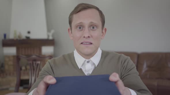 Portrait of Modestly Dressed Man Tremblingly Holding the Book, Looking Into the Camera