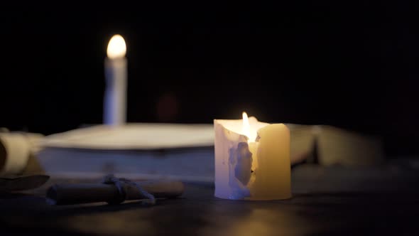 Burning candles next to historical book.