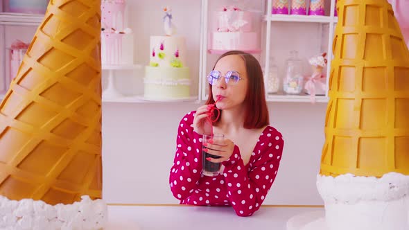 Woman drinking beverage near large decorative ice cream cones.