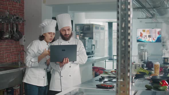 Team of Cooks Working on Professional Cusine Meal with Laptop