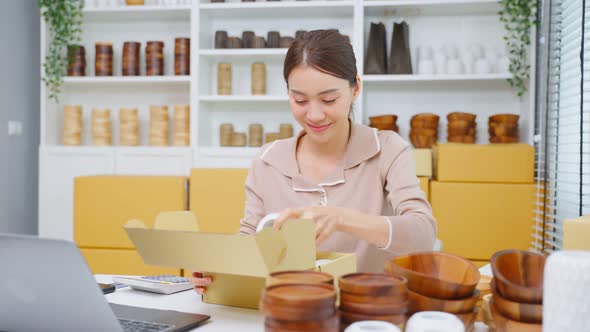 Asian beautiful woman packing vase goods order into box for customer.