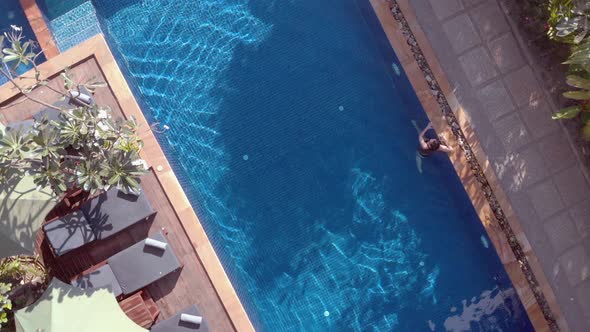 Slow Drone Shot Ascending and Rotating Above a Tropical Hotel Swimming Pool