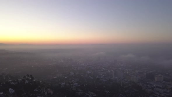 AERIAL: Over Hollywood Hills at Sunrise with View on Los Angeles in Clouds 