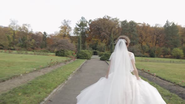 Beautiful and Lovely Bride in Wedding Dress Running in the Park. Slow Motion