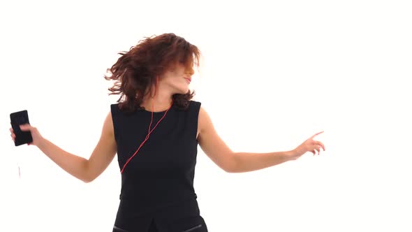 Joyful Young Girl in Black Dress Listening to the Music with Her Earphones and Having Fun Dancing