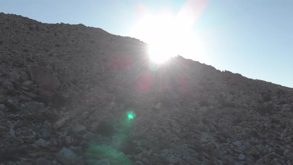 Aerial Slide Reveal of Morning Sun from Behind Rocky Hill