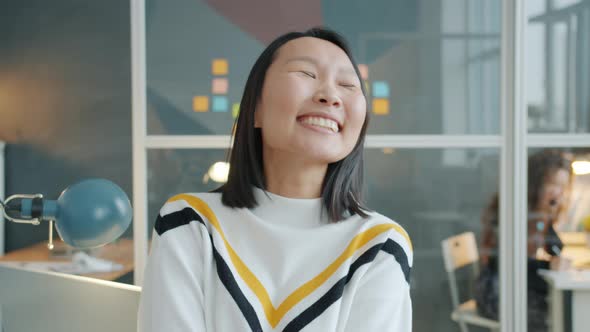 Portrait of Happy Asian Woman Smiling and Laughing Sitting at Desk in Office