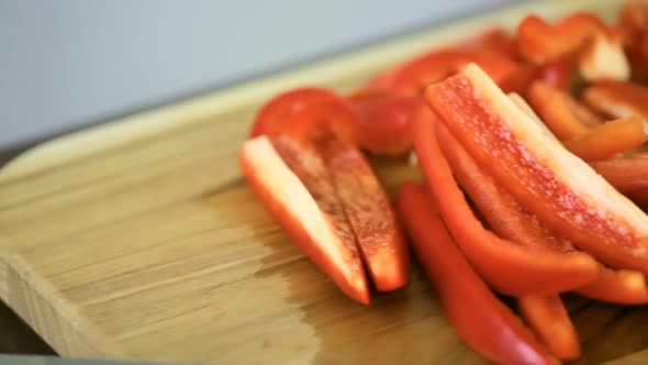 Slicing red bell pepper on a wood cutting board.