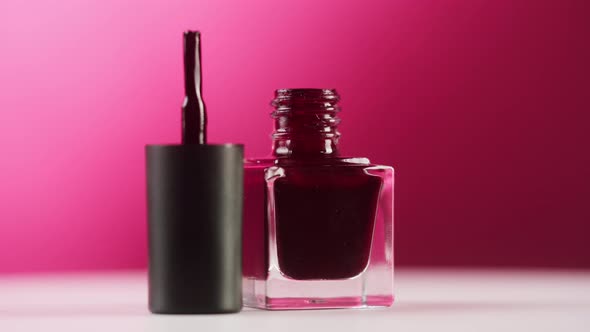 Opened Red Nail Polish Rotating on Pink Background