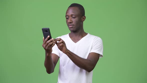 Young African Man Using Phone Against Green Background