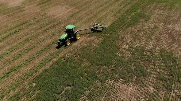 Aerial View of a Tractor with a Mower Mows the Grass on an Empty Field